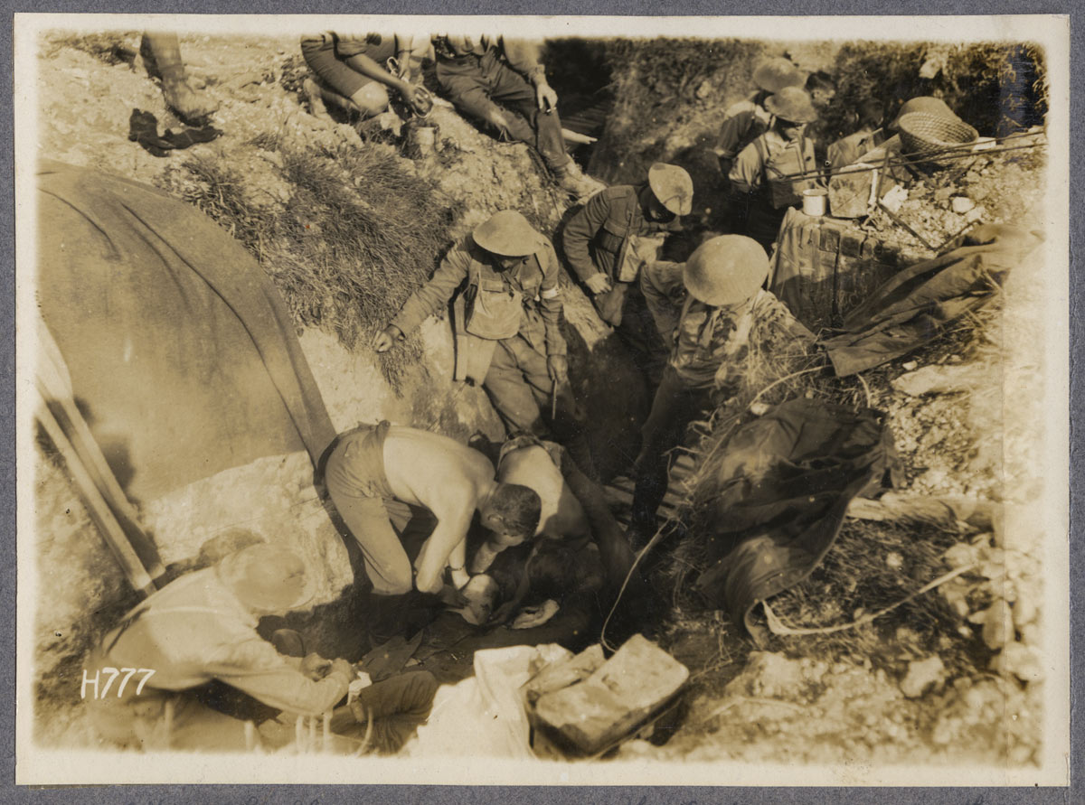 A doctor stripped to the waist bandaging a wounded New Zealand soldier after a highly successful raid, Gommecourt, July 1918.